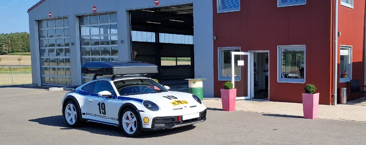 GTü Prüfstelle in Dahlenburg mit offenem Rolltor und einem Porsche in weiß davor