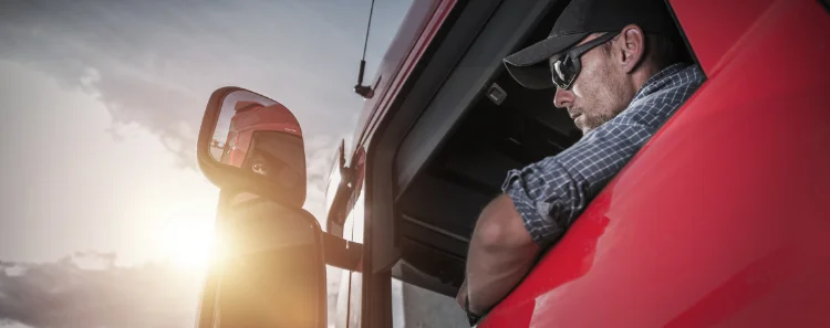 LKW Fahrer lehnt sich aus dem Fenster und Schaut beim Rangieren in den Rückspiegel